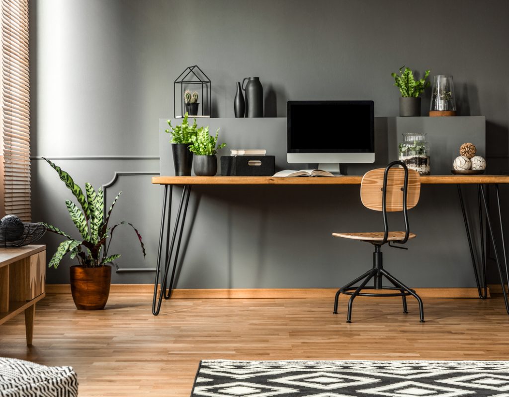 Real photo of a dark interior with wooden desk, chair and computer in the study space in the middle